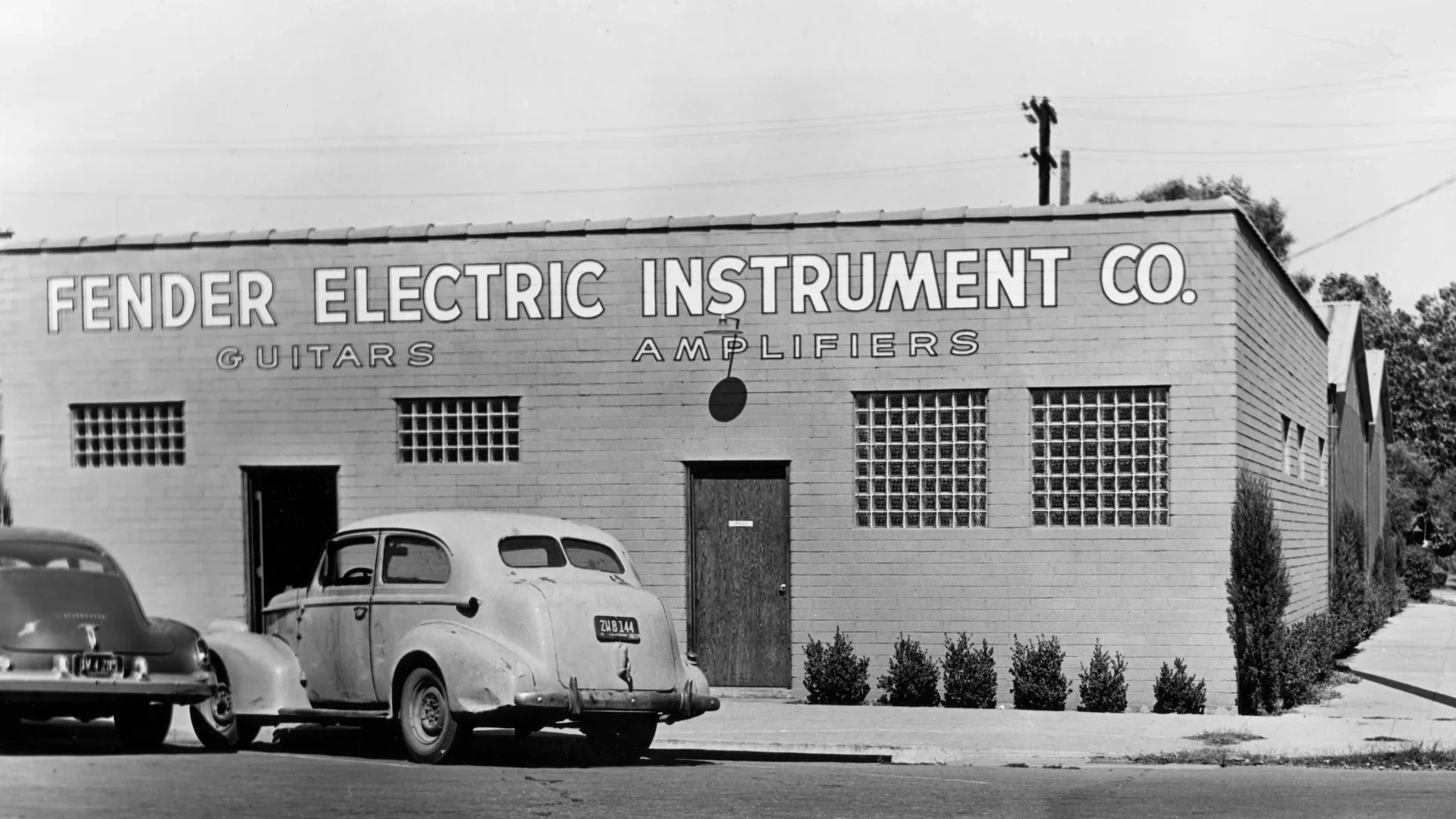 Fender Electric Instrument Co. building with parked cars in front.
