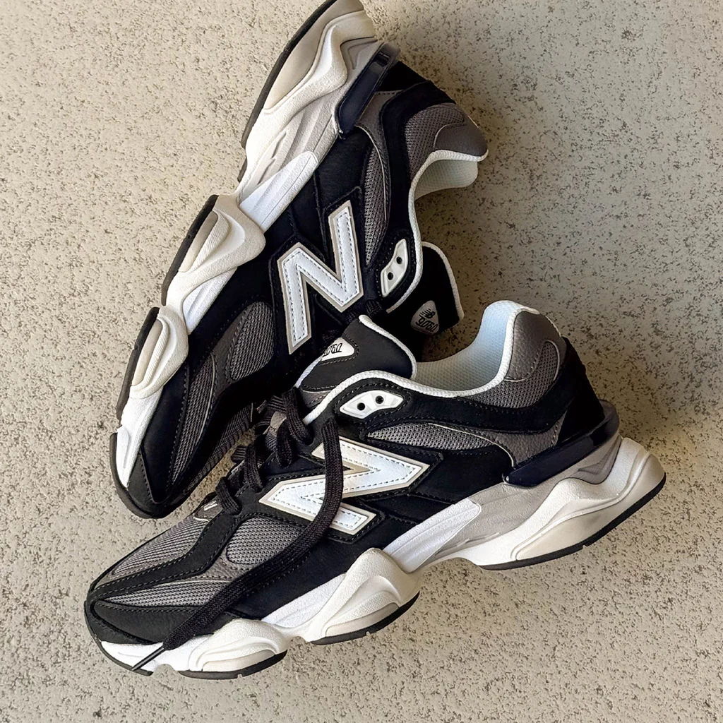 A pair of black and white New Balance sneakers on a concrete surface.