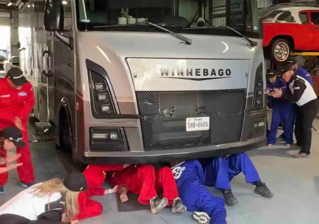 Mechanics working under a large truck in a garage.