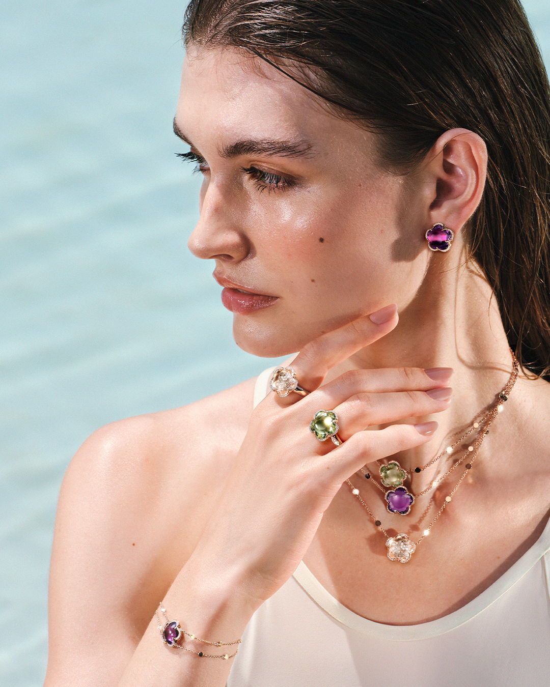 Model showcasing various jewelry pieces near water.
