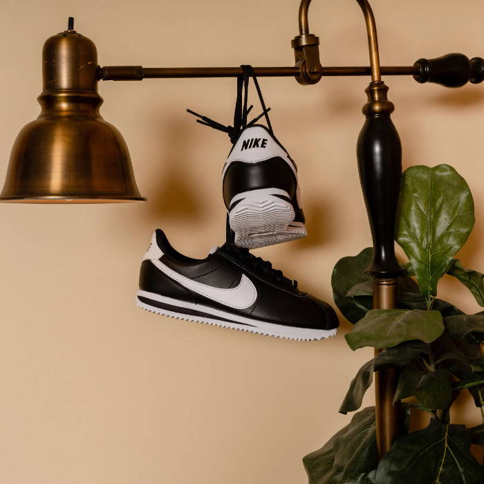 nike black and white cortez hanging on gold light