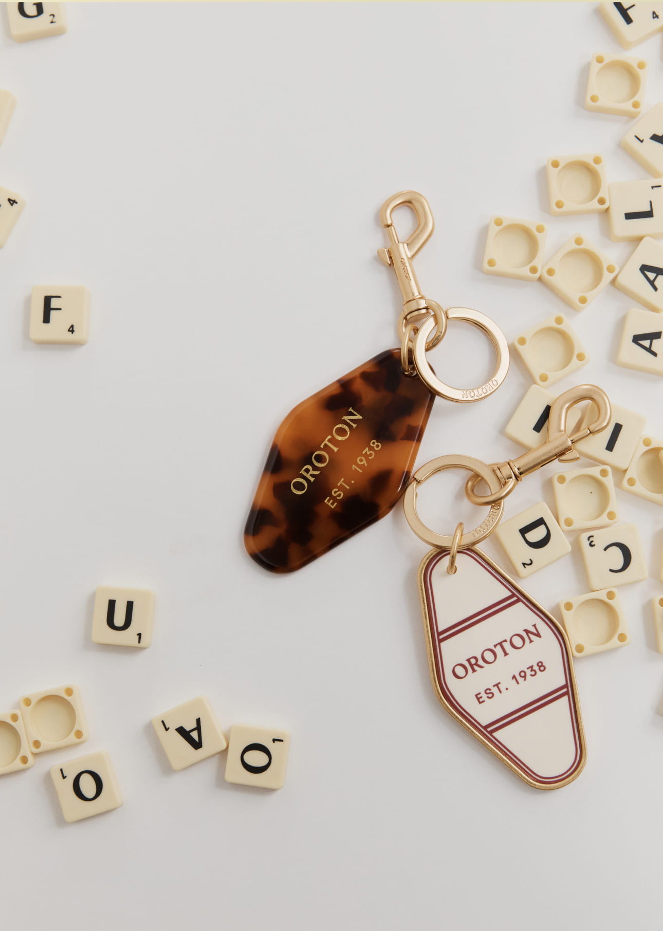Two keychains on a white surface surrounded by scattered letter tiles.