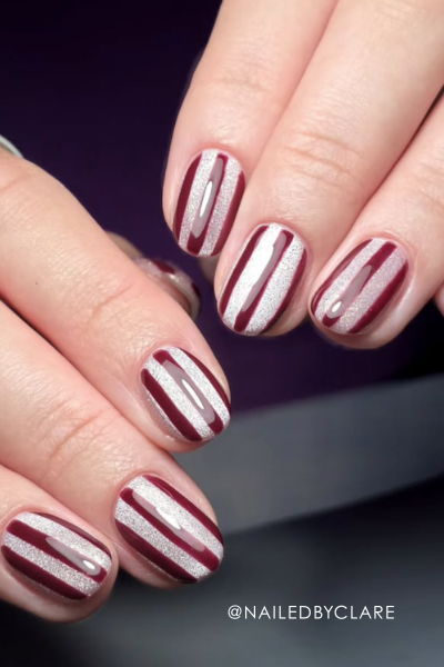 Nail art featuring red and white striped designs on manicured fingers.