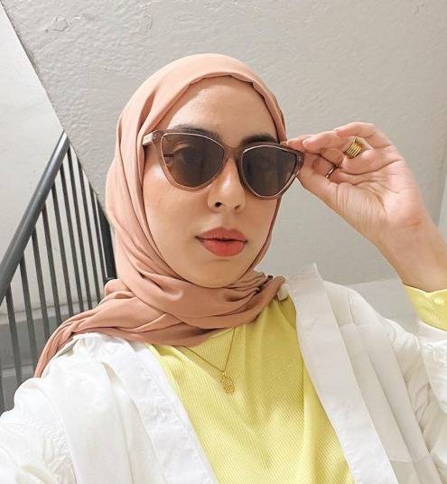 Woman wearing a pink headscarf, a yellow and white shirt and Audrey sunglasses, high end oversized sunglasses