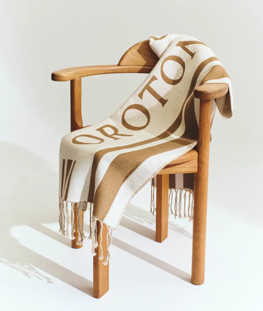 A wooden chair with a patterned blanket draped over it.