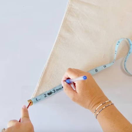 Using a heat-erasable pen and measuring tape to mark a 4-inch semicircle stem hole in the flower bag fabric