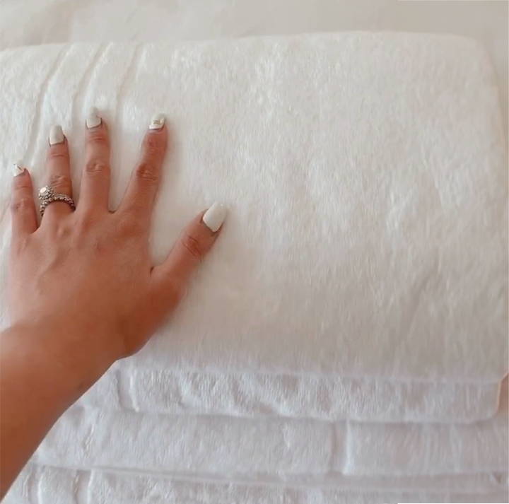 A woman touching a soft stack of white towels - Play Video Review