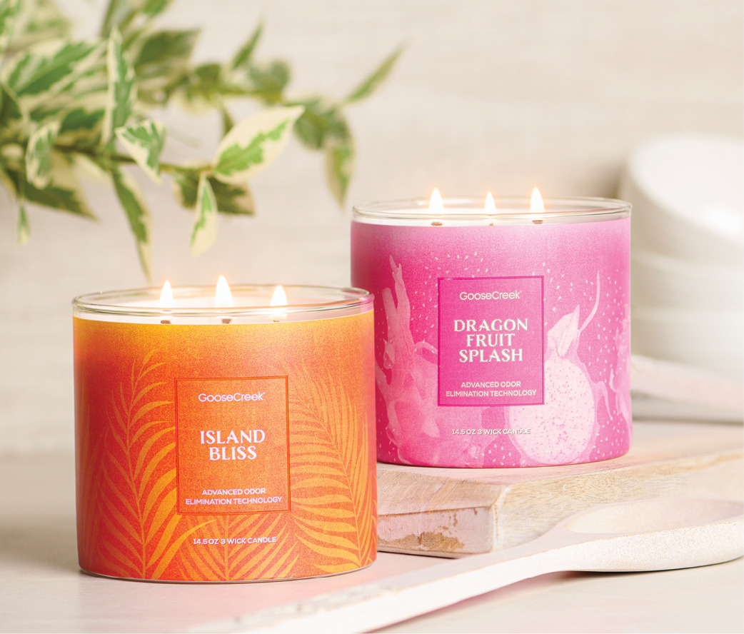 Two scented candles in decorative jars on a wooden surface.