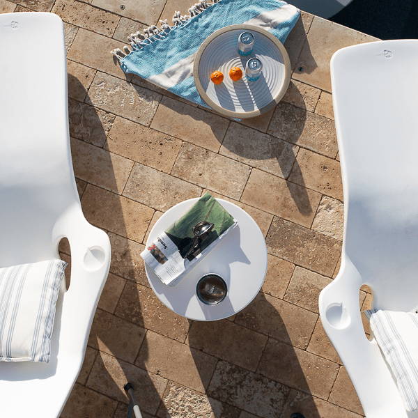 Two poolside lounge chairs with. aplatter and side table between them.