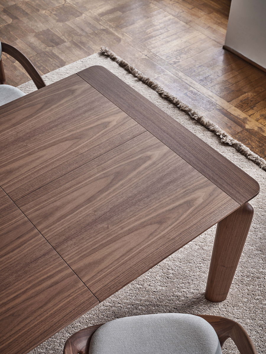 Top view of a wooden Amphora Extendable table by Porada with a textured surface and adjacent chair.