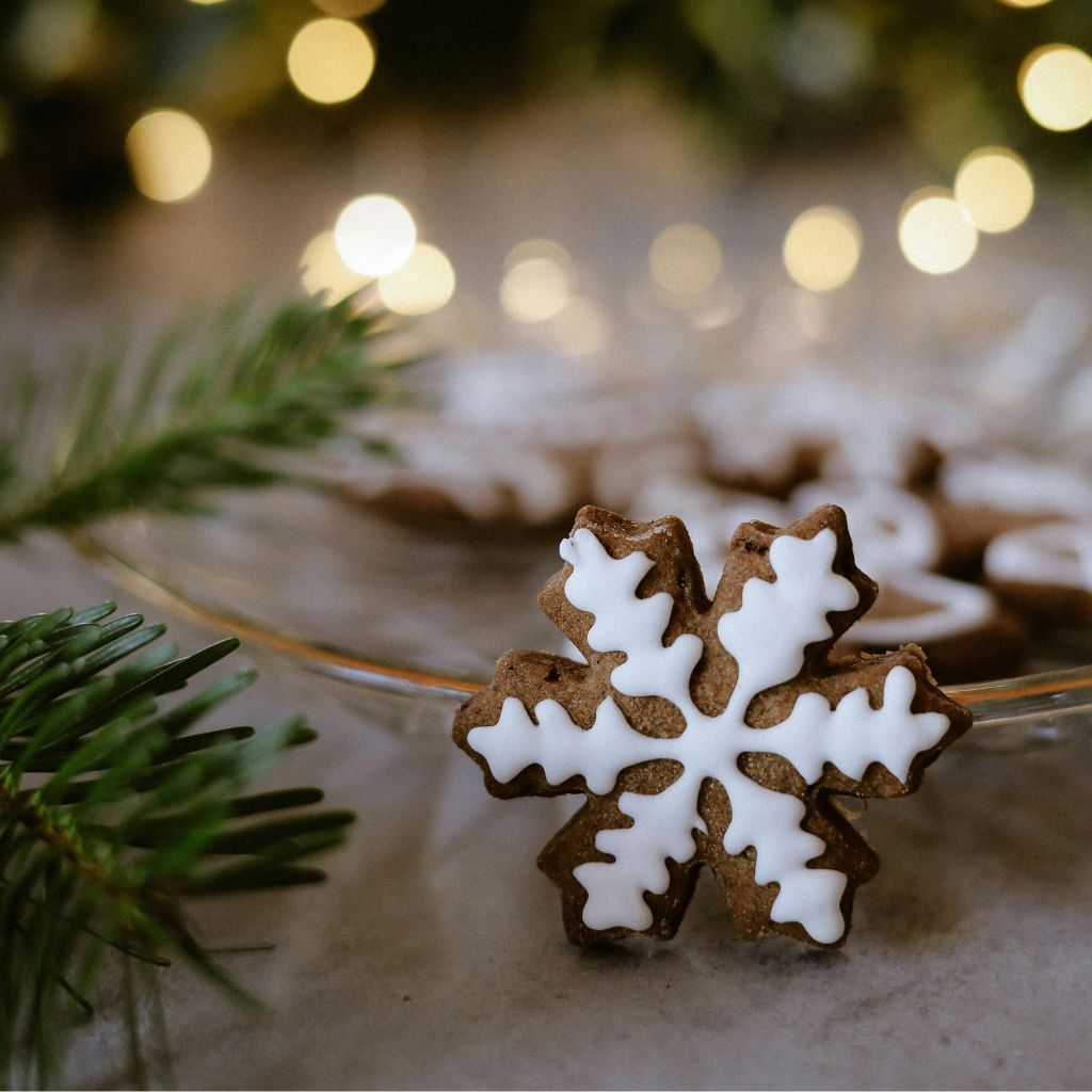 Lebkuchen-Schneeflocken-Plätzchen mit Zuckerguss und sanften Lichtern im Hintergrund.