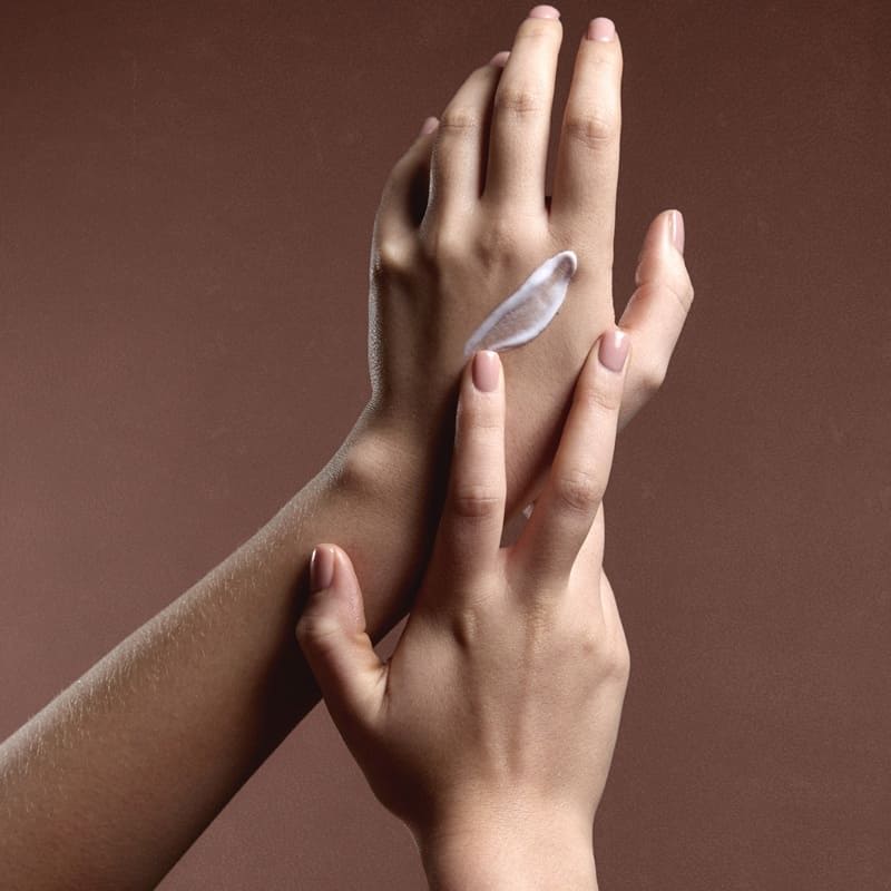 Two hands gently touching, one with a small object on it.