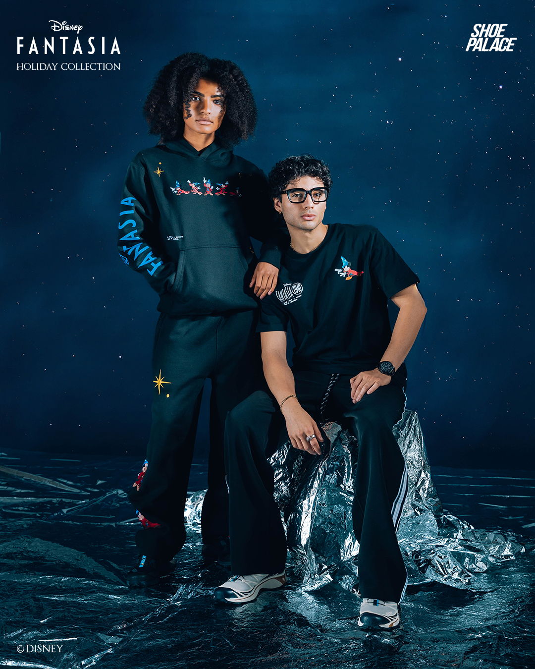 Two individuals in stylish outfits pose against a starry background.