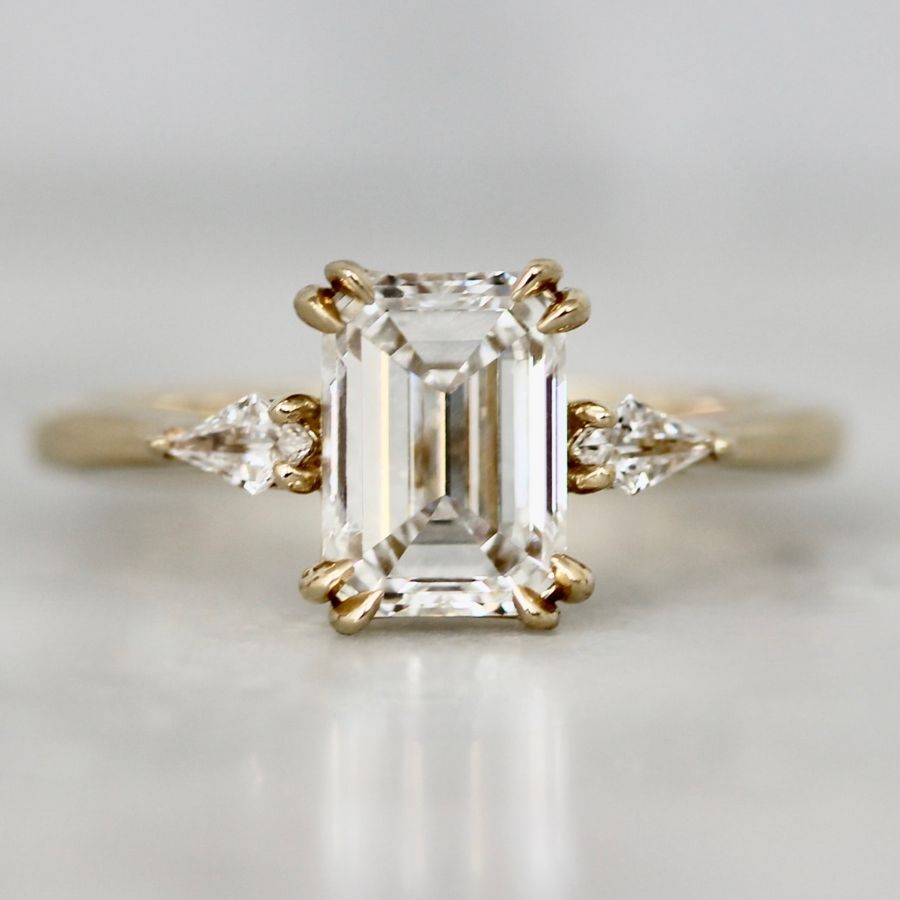 White emerald cut lab diamond ring with shield cut side diamonds
