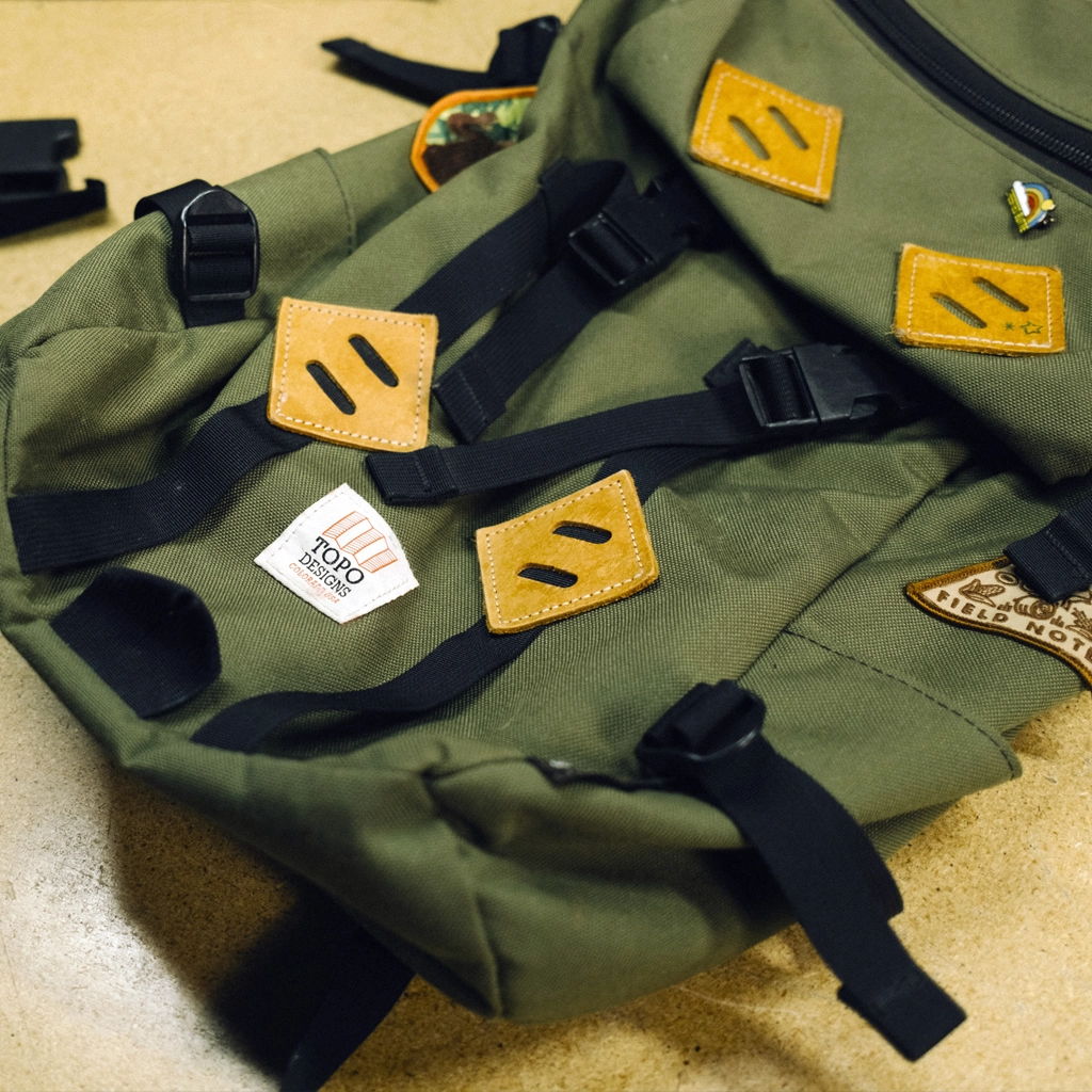 Green backpack with yellow patches and black straps on a surface.