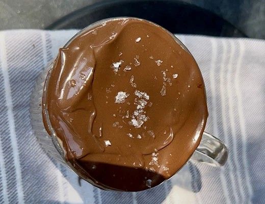 A cup of chocolate topped with a sprinkle of salt.