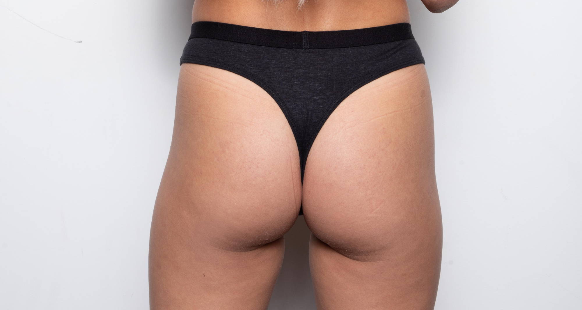 a woman’s butt wearing a black thong with her blonde hair falling to her waist