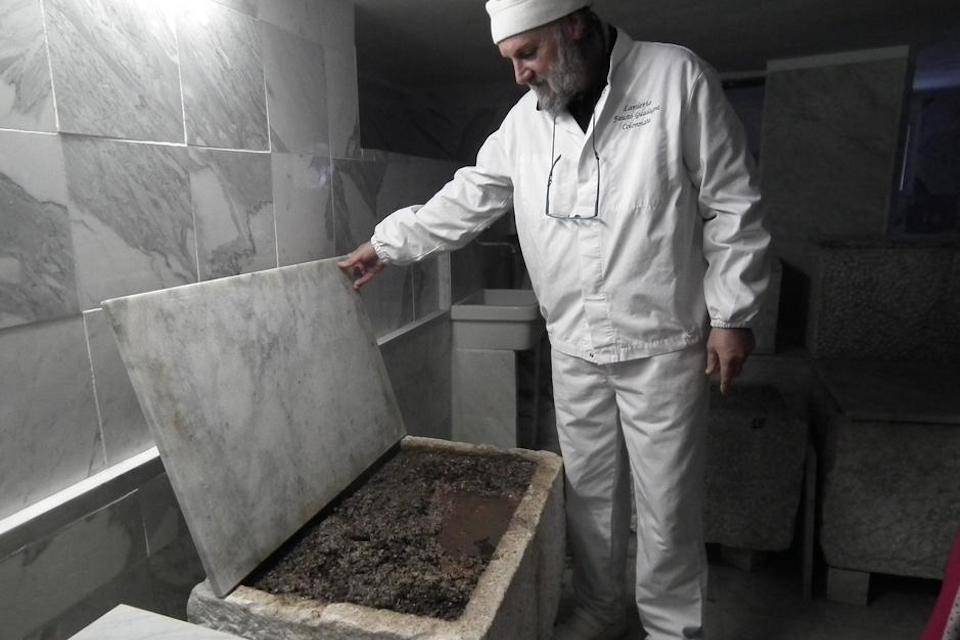 Fausto dressed in special clothing inspects Lardo being preserved in marble