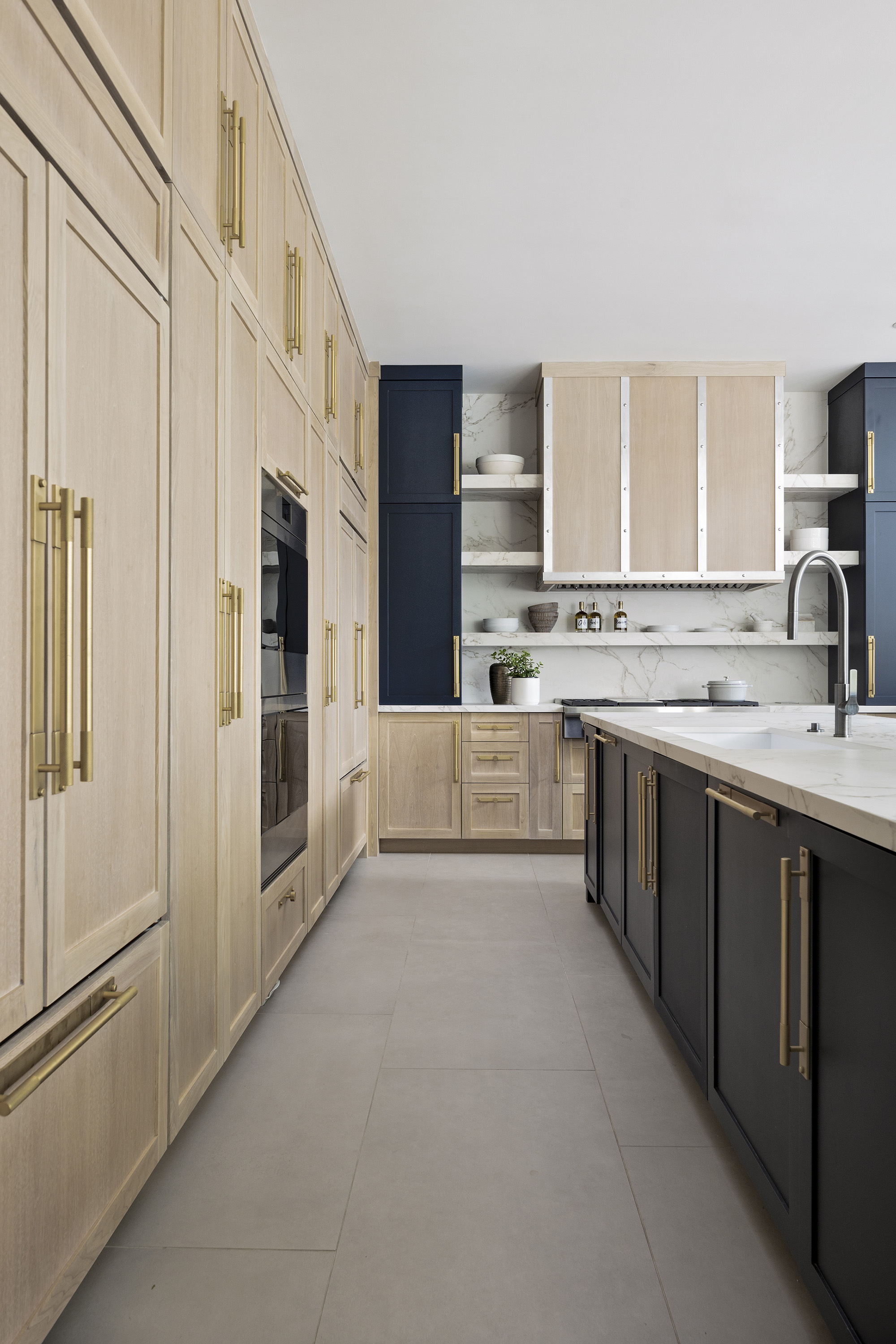 light wood and navy kitchen with island, finished with brass kitchen cabinet handles, tiled floor and marble worktops. Design by HW Interiors Wellington