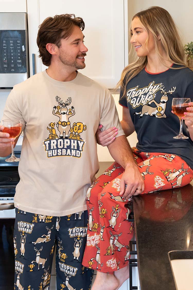 Couple in matching pajamas, holding drinks and smiling at each other.