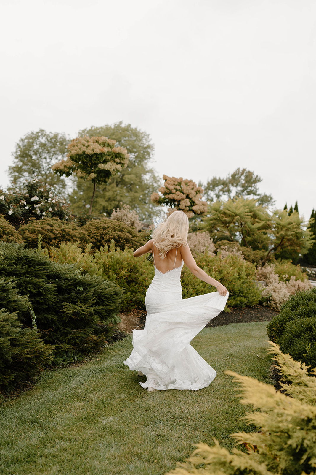 Bride in a white gown twirling in a garden.