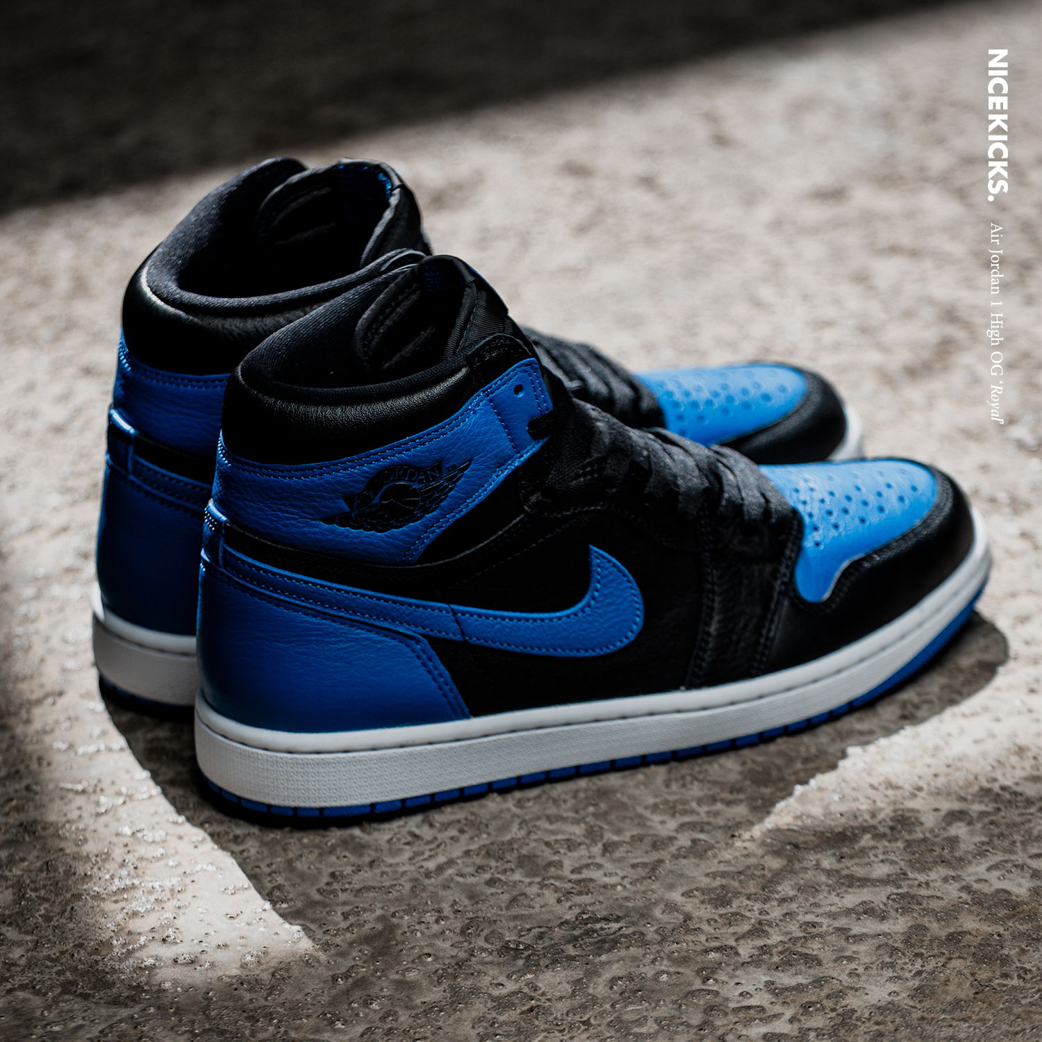 Black and blue Nike Air Jordan sneakers on a textured surface.