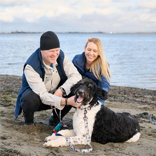 A couple with a dog at the beach.