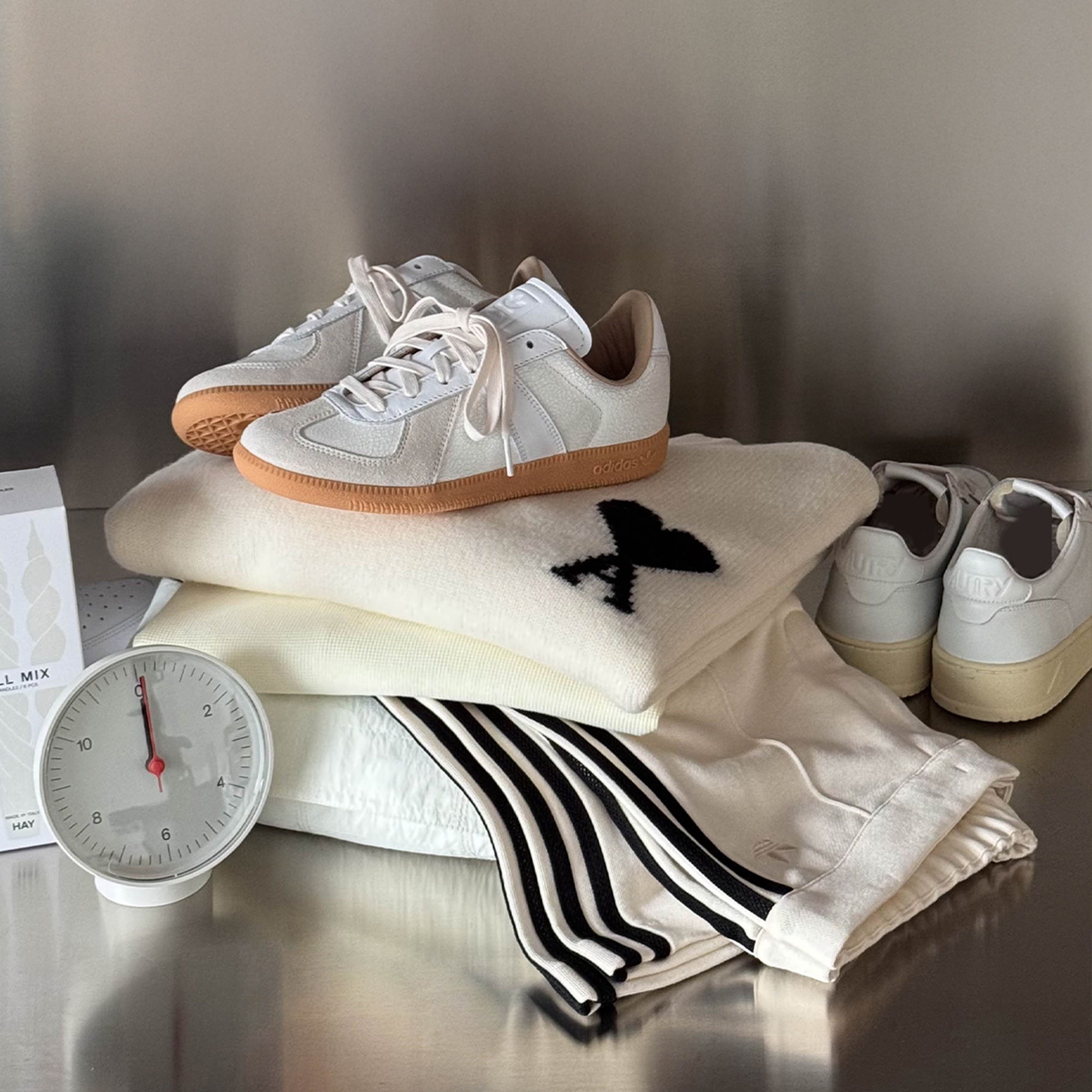 A pair of sneakers, clothing, and a clock on a surface.