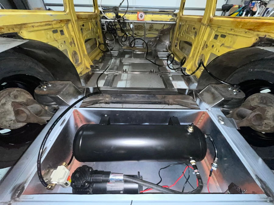 Rear floor-mounted black air tank and compressor setup inside 1982 Volkswagen Rabbit Slam air system gallery photo 5