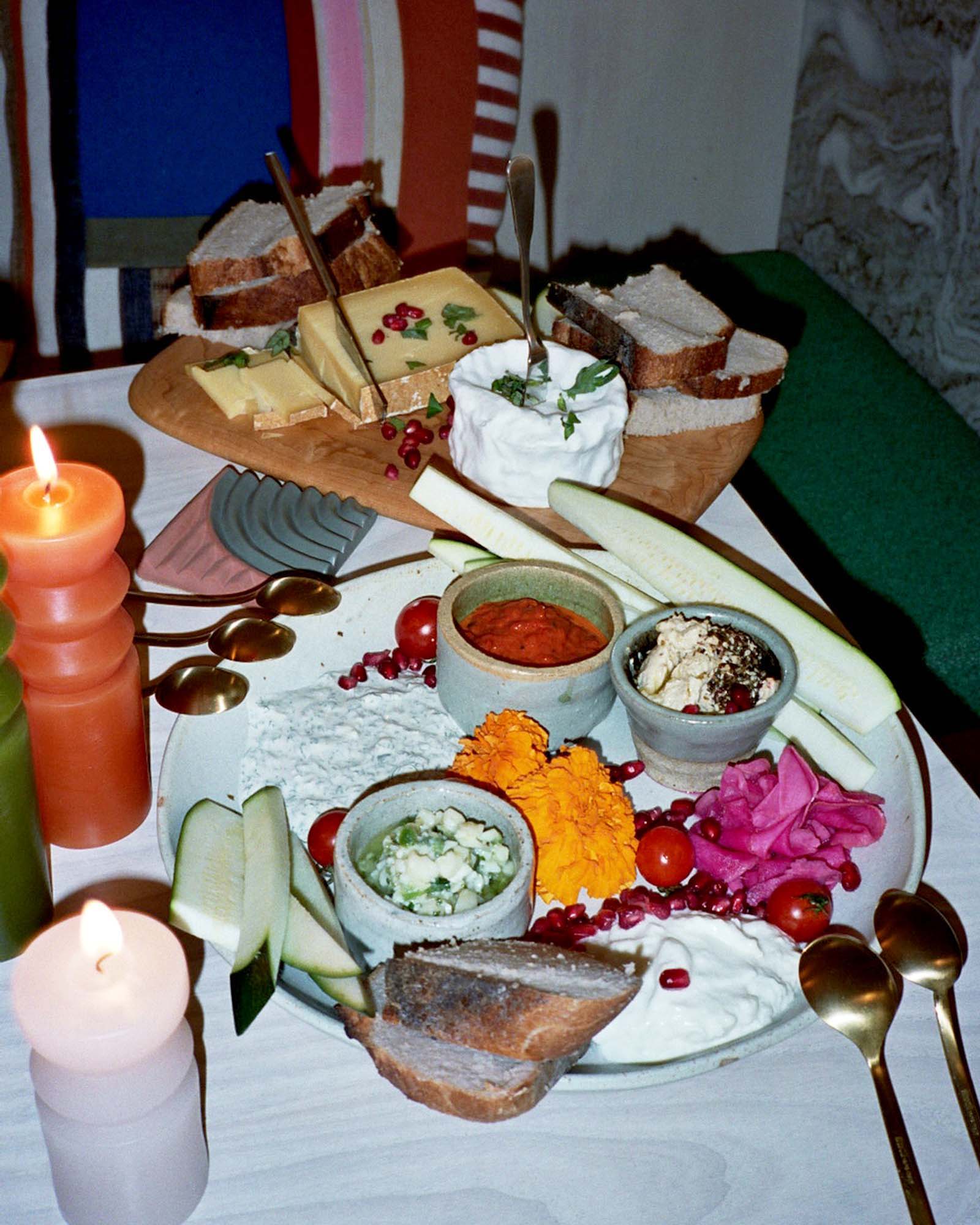 A close up image of the dinner table, with chessboard, a plate of various dips, and areaware candles.