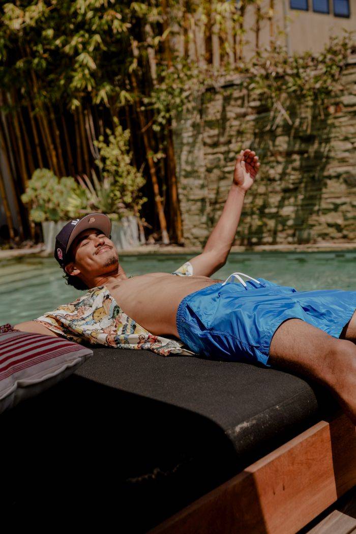 male model wearing maison article apparel laying by pool