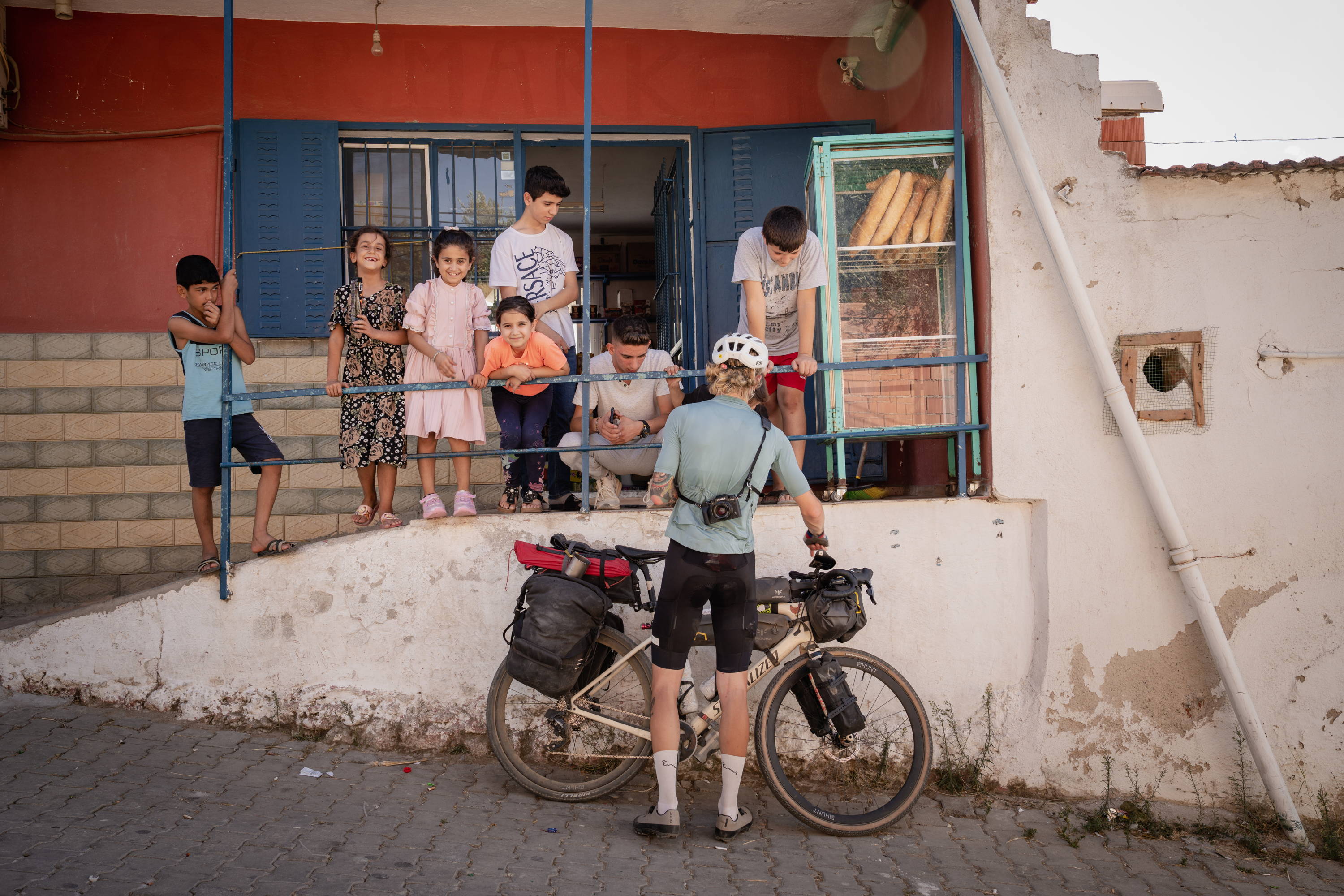 Boru standing his bike up against a wall with smiling kids watching