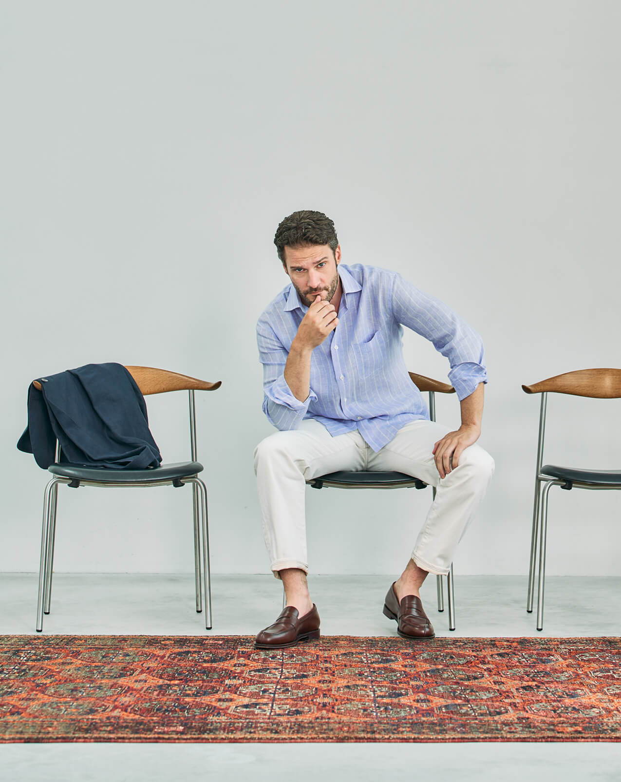 Man in a blue shirt and white pants sitting on a chair.