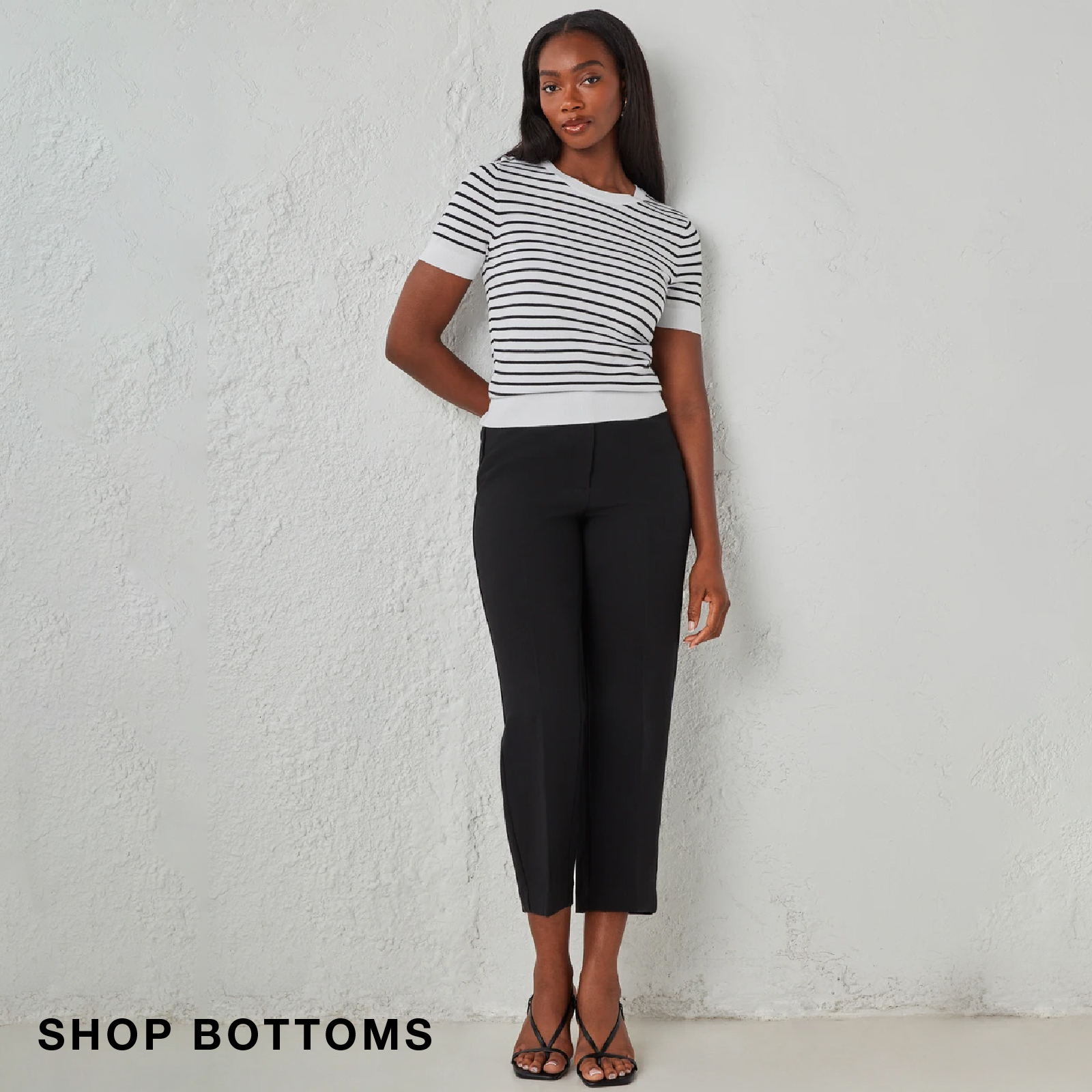 Woman in striped top and black pants posing against a light background.