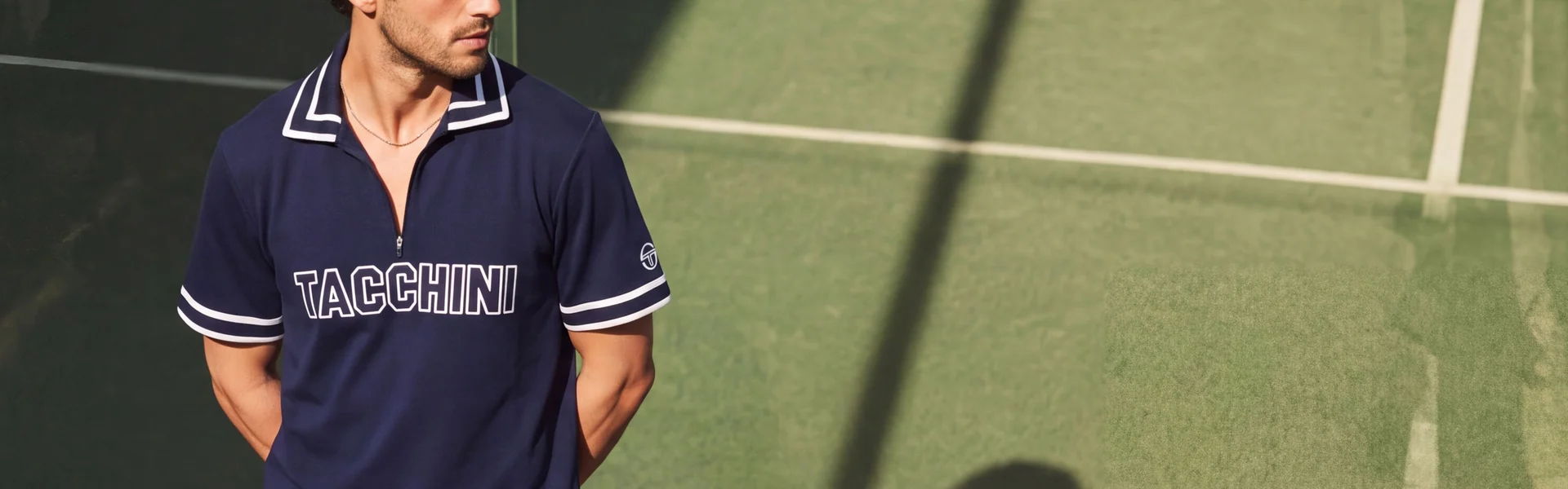 Man in a navy Sergio Tacchini polo shirt standing on a tennis court.