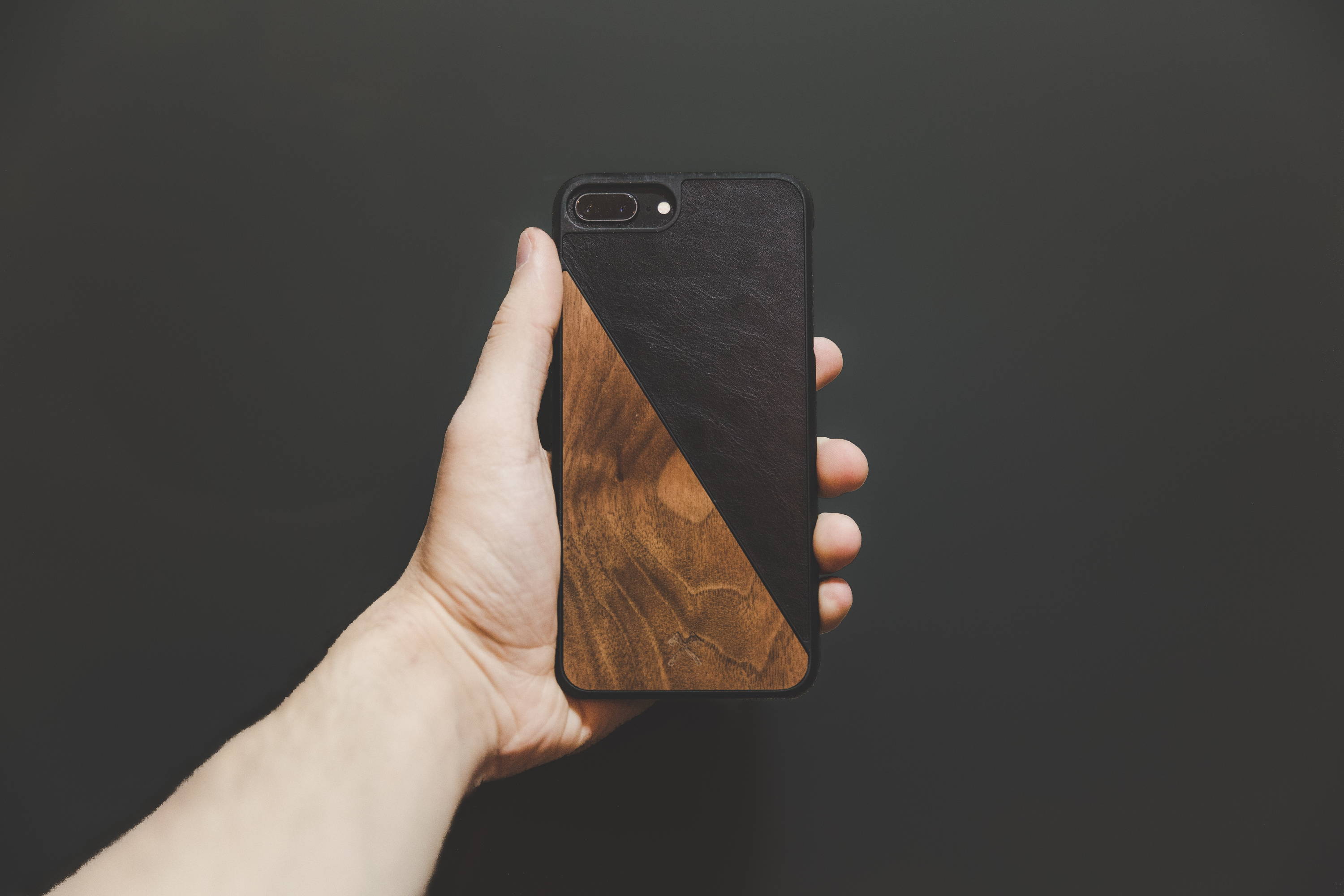 a hand holding a phone with a wooden case
