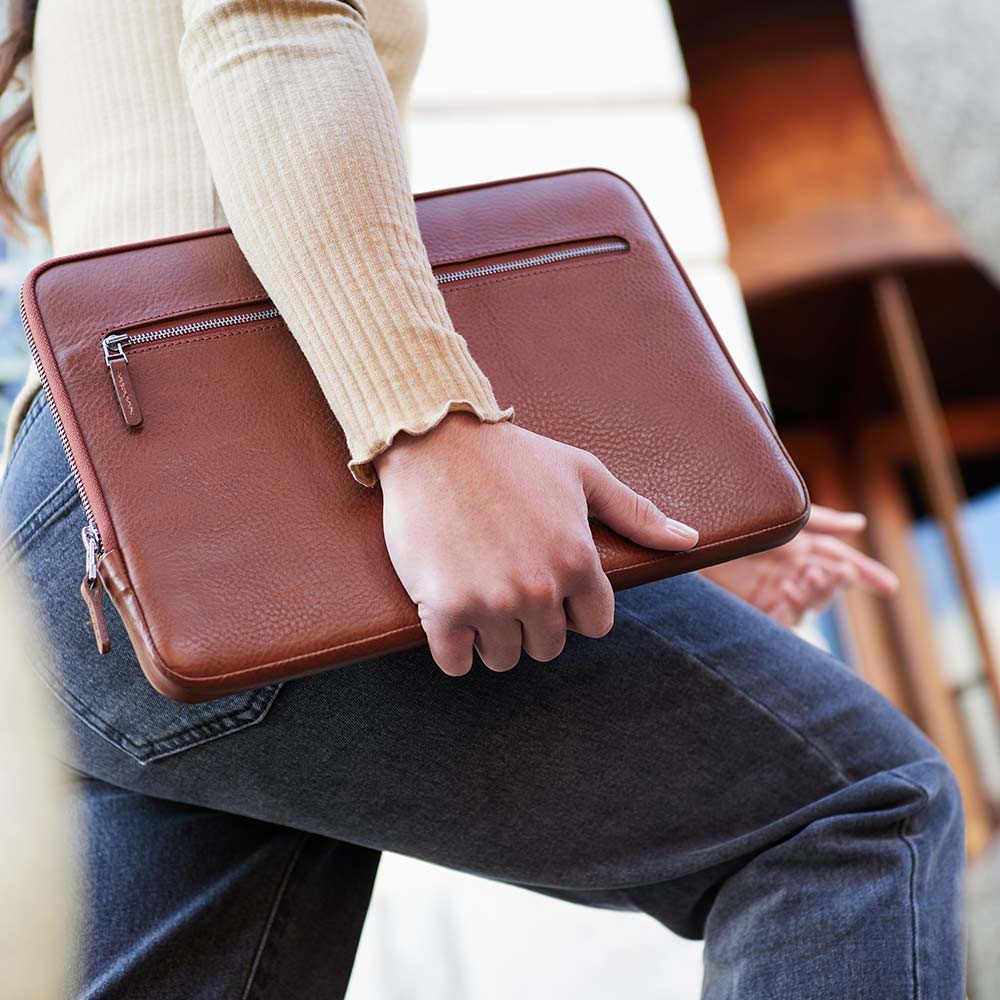 Eine Frau hält eine Macbook Hülle von Godo Wihelm unter dem Arm