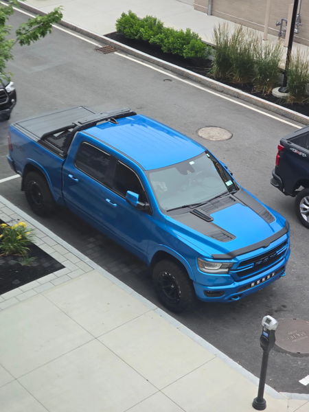 High-angle view of blue RAM 1500 with tonneau cover and sports bar in parking lot