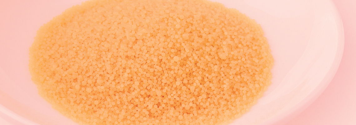 A pile of orange-colored granulated substance on a pink plate.