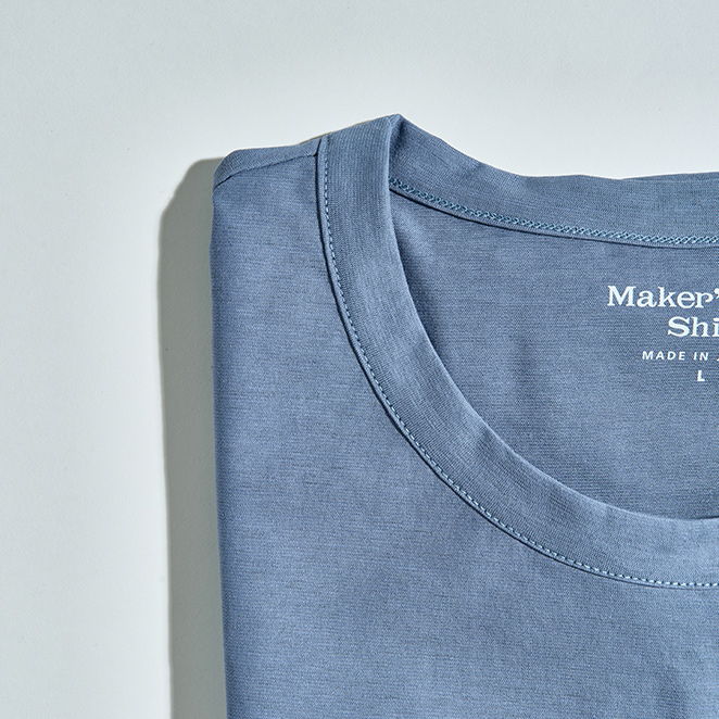 Folded blue shirt with a round neckline and label.
