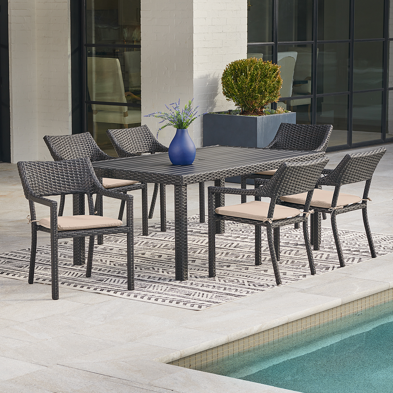 Outdoor dining table with six chairs beside a pool.