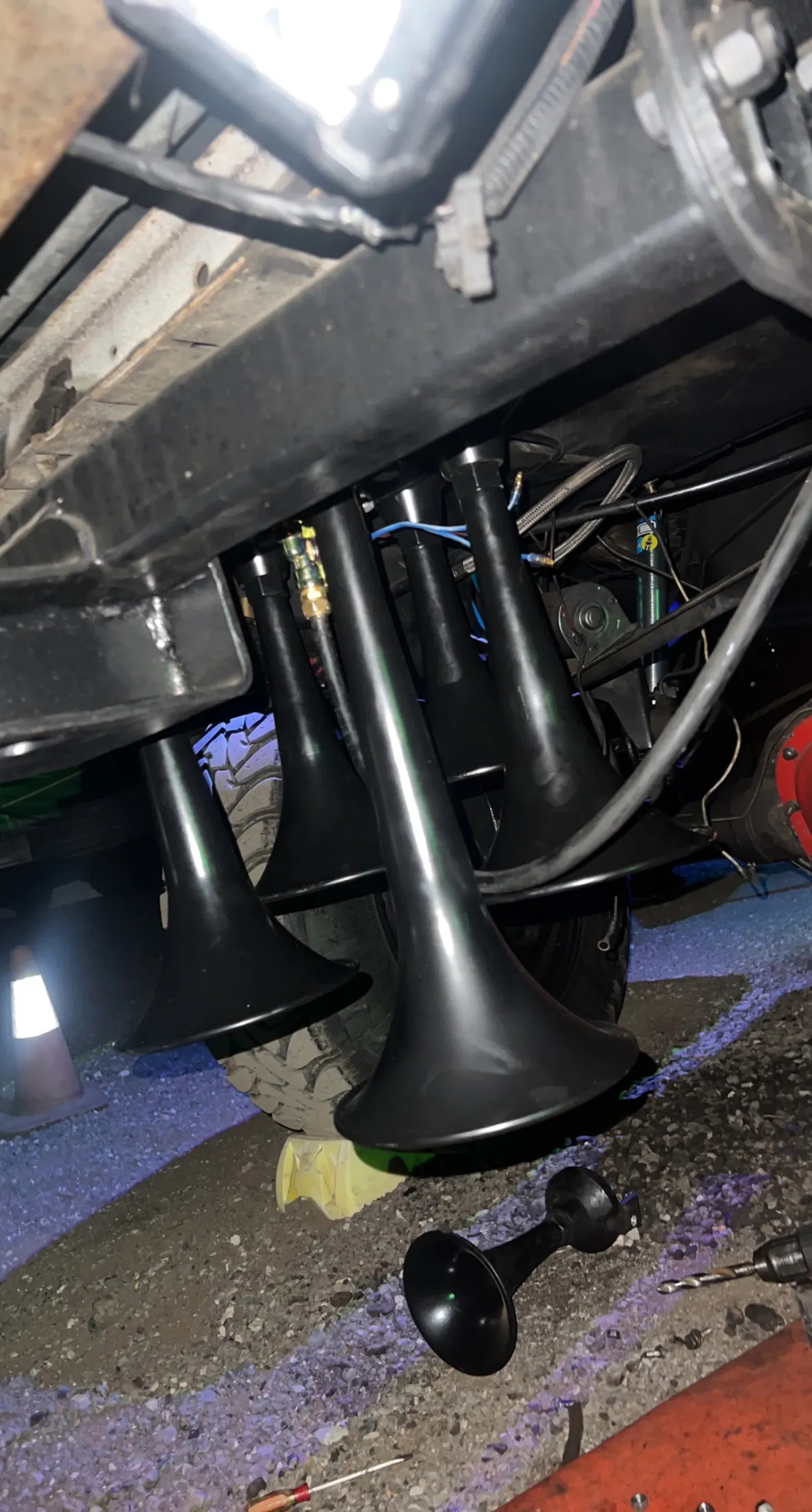 Four black train horn trumpets mounted to the undercarriage of Trevour's Ford F250 during installation