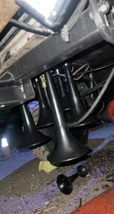 Four black train horn trumpets mounted to the undercarriage of Trevour's Ford F250 during installation