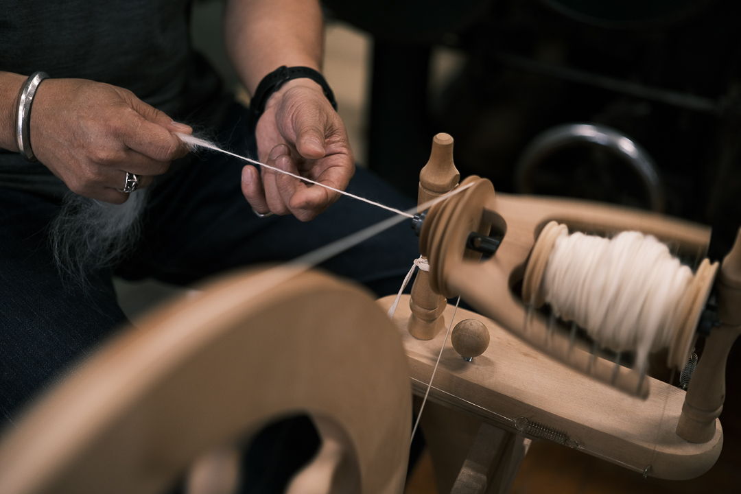 Person using a spinning wheel to create yarn.