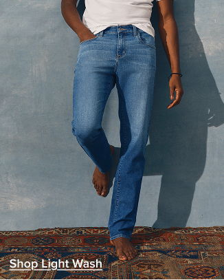 Person wearing light wash jeans, standing barefoot on a patterned rug.