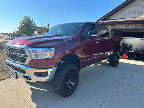 Rear three-quarter view of lifted maroon Ram 1500 Big Horn 4x4 on suburban driveway