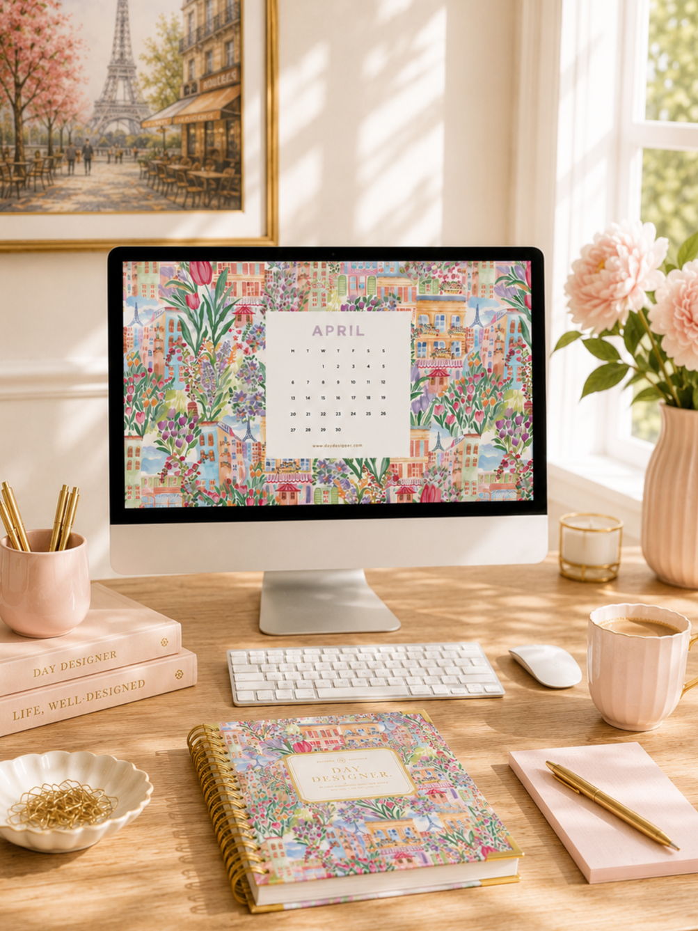 april 2026 digital wallpaper shown on desktop, white keyboard, wood desk, planner, notepad, pen, dish with paperclips, books, pencils in cup, coffee, vase with flowers, Parisian picture in frame on wall