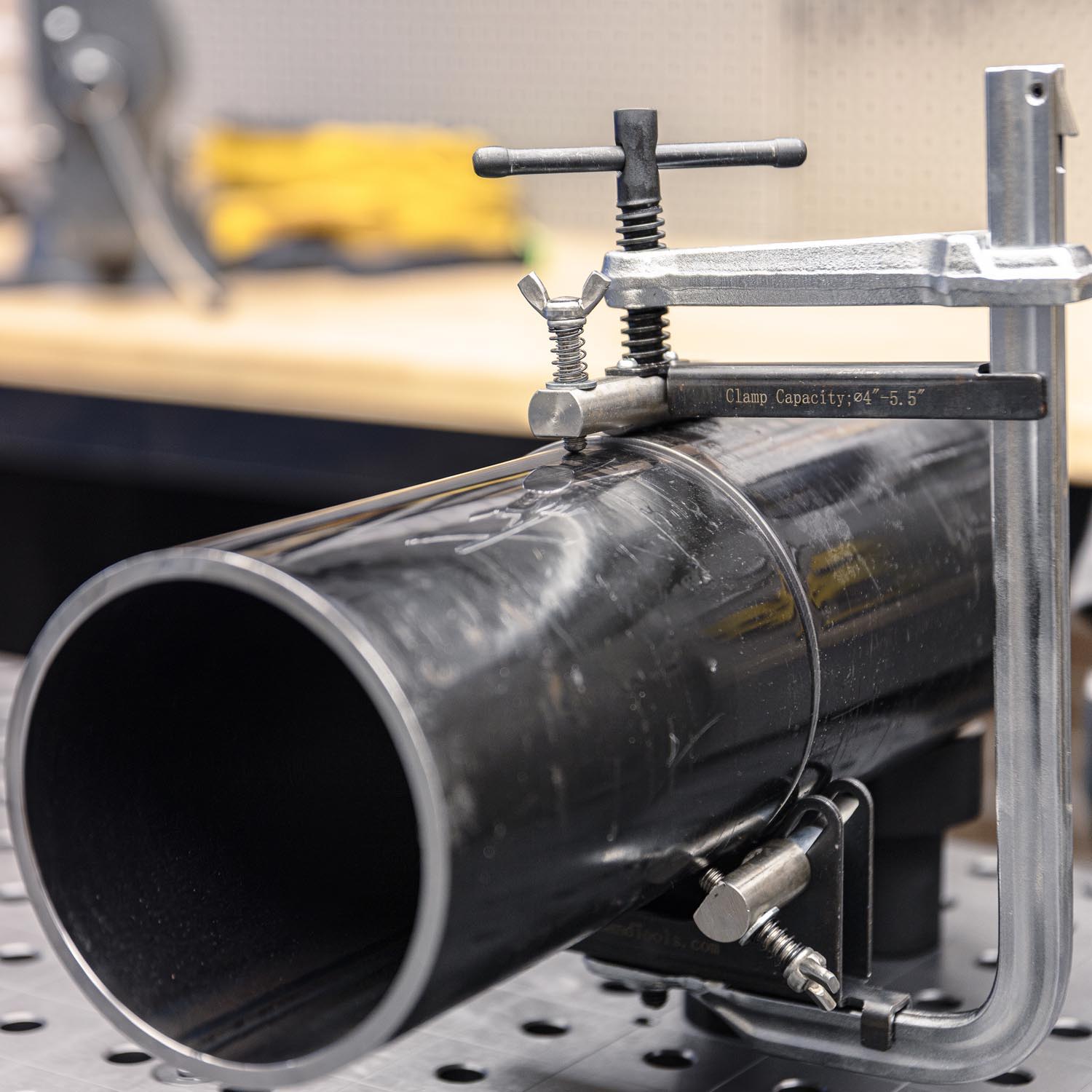A black pipe secured with a clamp on a workbench.