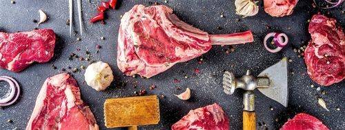 Raw cuts of red meat with ax and wood cleaver