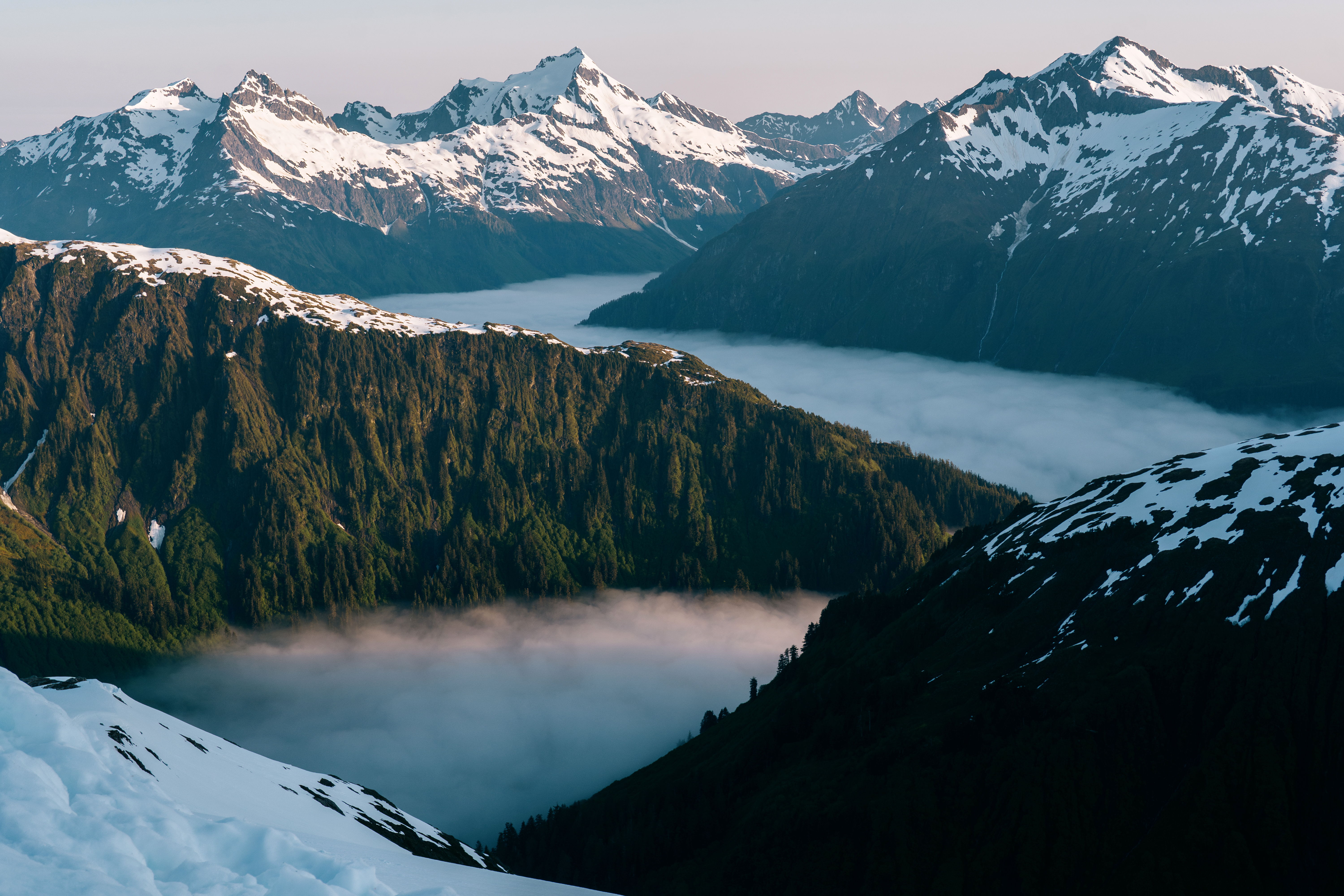 Snow-capped mountains overlook a misty valley at dawn.